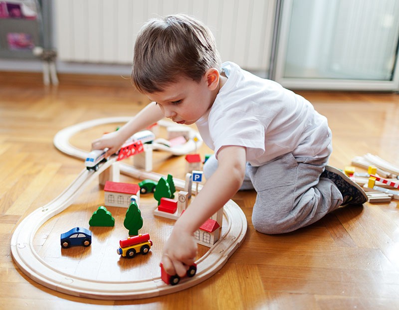 Hearthwood Floors - Little boy playing with a train set on a hardwood floor