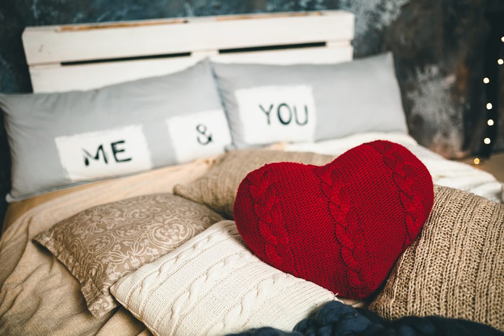 Bed decorated for Valentine's Day with red throw pillow
